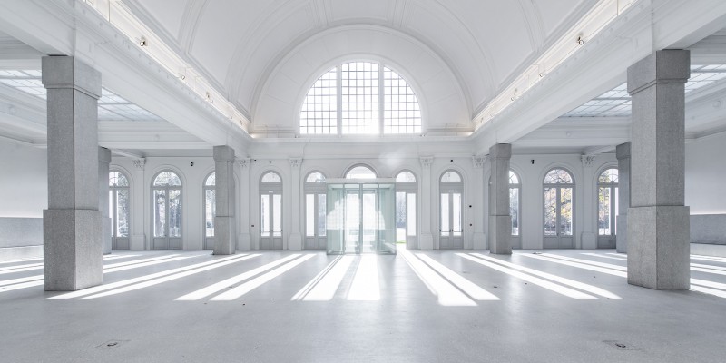 De zaal heeft grote boogramen, een terrazzovloer en zuilen bekleed met terrazzoplaten.