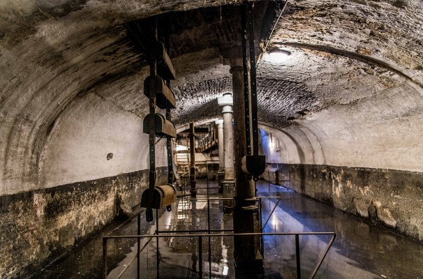 Ondergronds waterreservoir waarin een metalen noria met waterbakken voor waterverplaatsing naar hogergelegen reservoir zorgt