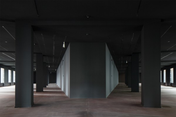 Lege exporuimte van het ModeMuseum met veel ramen en donkere zuilen en muren.