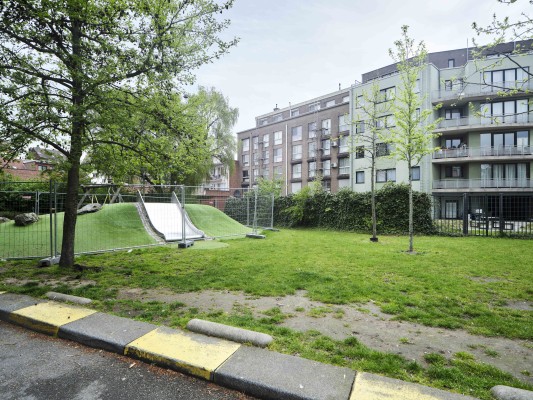 Aan de achterzijde kijken de appartementen Hogeweg 20-22 uit op een publieke groene ruimte met speeltuin