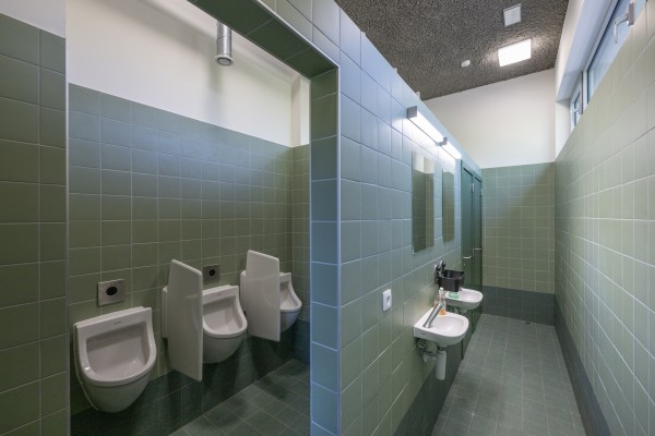 Meerdere toiletten met groene tegels aan de muren