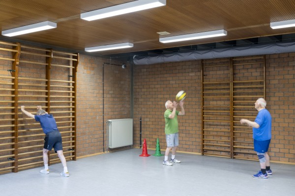 Drie senioren die aan het sporten zijn in een kleine sporthal