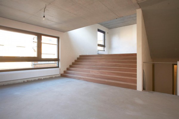 De leefruimte ligt op split level, en staat dankzij een kamerbrede trap in verbinding met de open keuken.