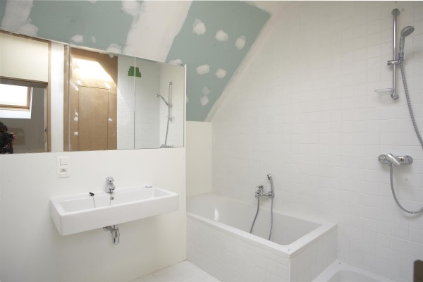 Badkamer voorzien van bad, douche, lavabo en spiegel. Muren zijn nog te schilderen.