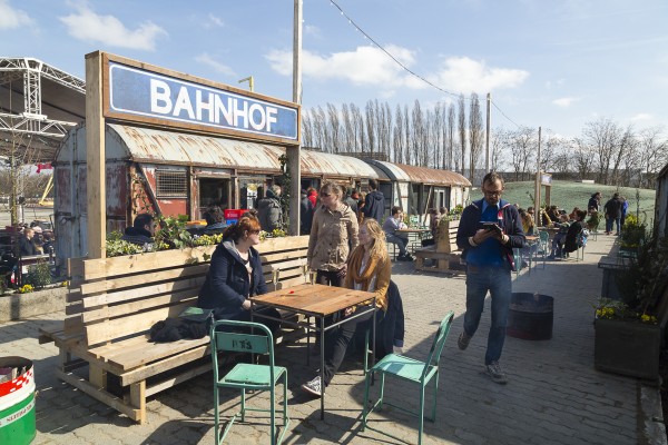 Mensen drinken gezellig iets aan café Bahnhof op het openingsfeest van Spoor Oost