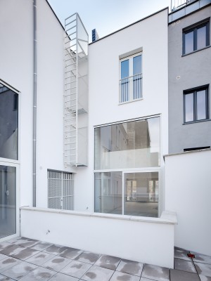 Achtergevel met terras van de woning aan Lange Beeldekensstraat 1. Een grote glazen deur en raam plaatsen het terras in verbining met de leefruimte.