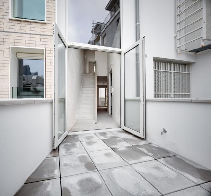 Een grote glazen deur geeft toegang tot het terras van de woning aan Lange Beeldekensstraat 1. Het terras is aangelegd op betontegel. 