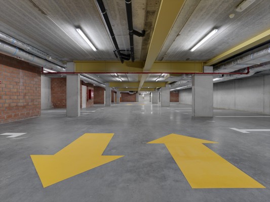 Ondergrondse parking in de Du Montstraat. Gele pijlen op de betonnen vloer geven de rijrichting aan.