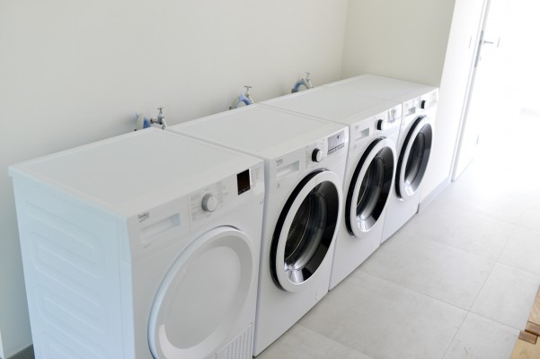 Gemeenschappelijke wasplaats met wasmachines en droogtrommel.