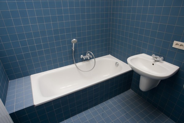 Badkamer is blauw betegeld en voorzien van ligbad en wastafel.