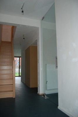 Gang met trap naar bovenverdieping. De glazen deur geeft toegang tot de leefruimte.