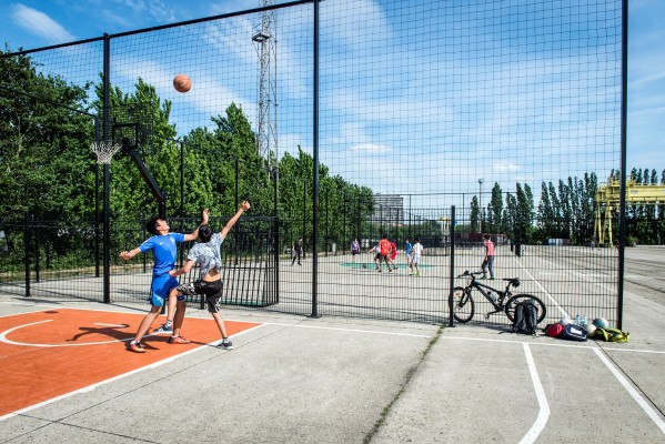 Jongeren zijn aan het basketten en het voetballen op de sportvelden op Spoor Oost 