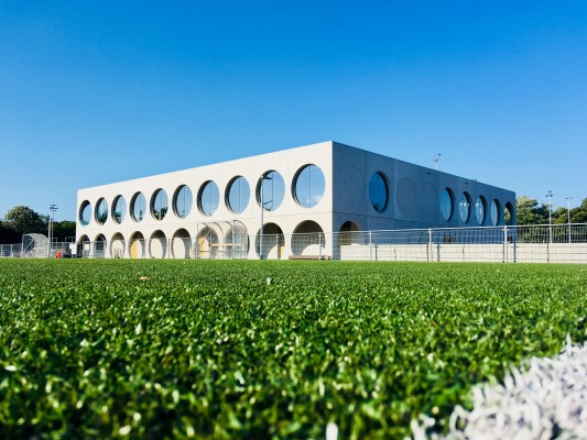 Een sportveld met kunstgras met op de achtergrond het sportcentrum.