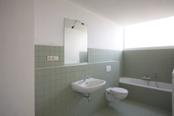 Badkamer is groen betegeld en voorzien van lavabo met spiegel, toilet en ligbad.