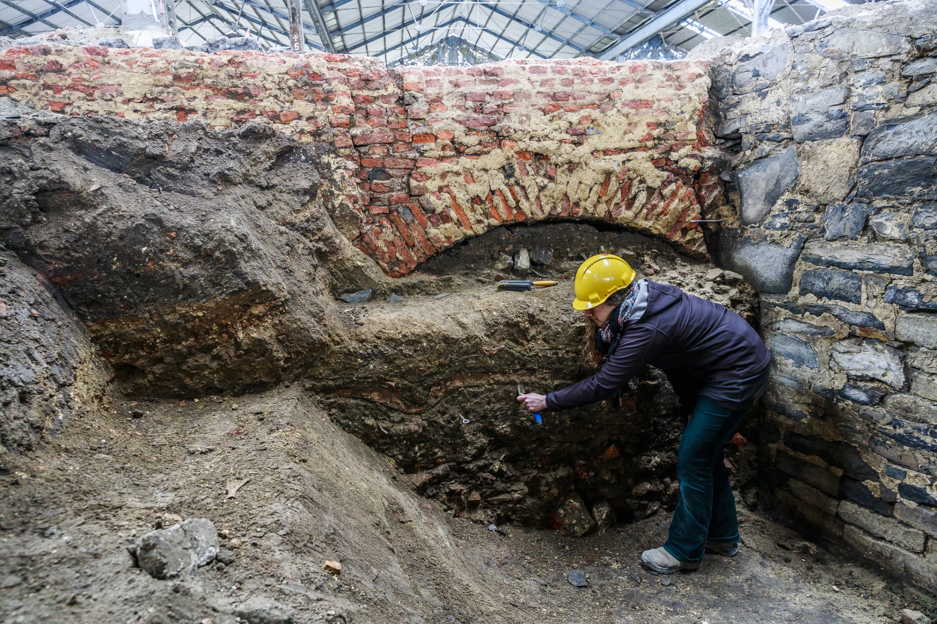 Archeologen onderzoeken de dempingslaag van de gracht in de historische burchtzone. Boven op de dempingslaag is een funderingsmuur (spaarboog) te zien van een later gebouw.