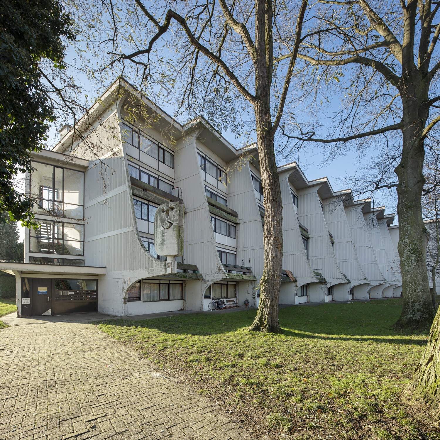 Appartementen in de Arenawijk met gras en bomen op de voorgrond.