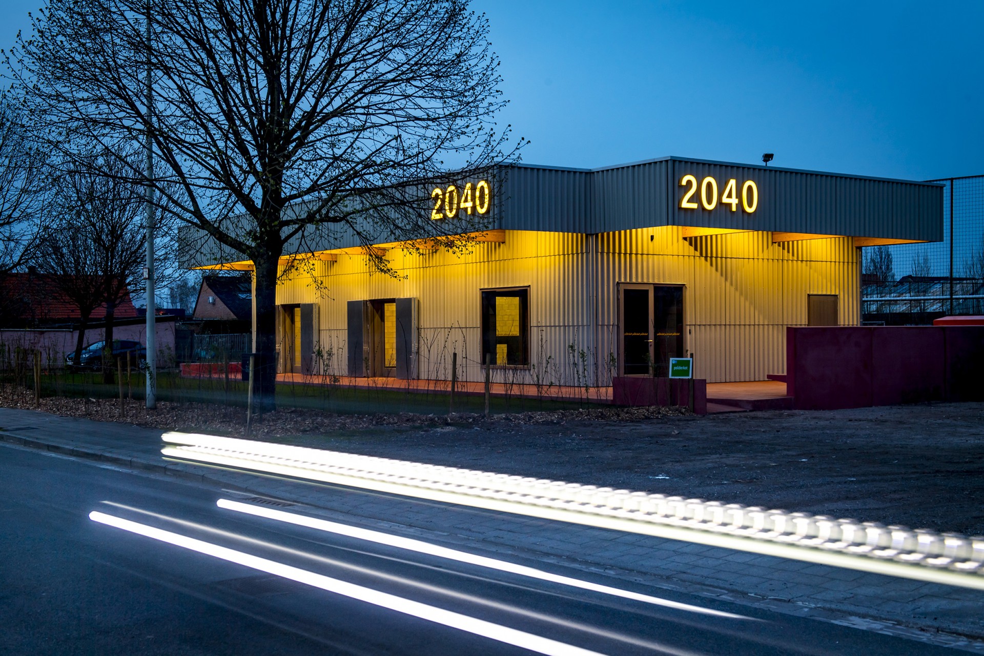 De gevel van het jeugdhuis is 's avonds verlicht.