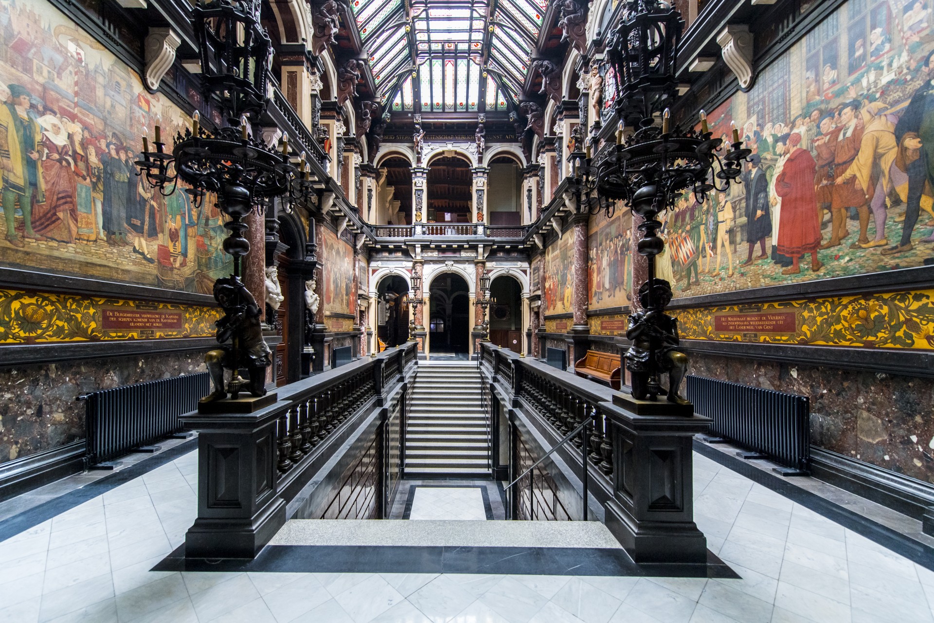 monumentale trap in het midden van het stadhuis met langs beide zijdes grote schilderingen op doek.