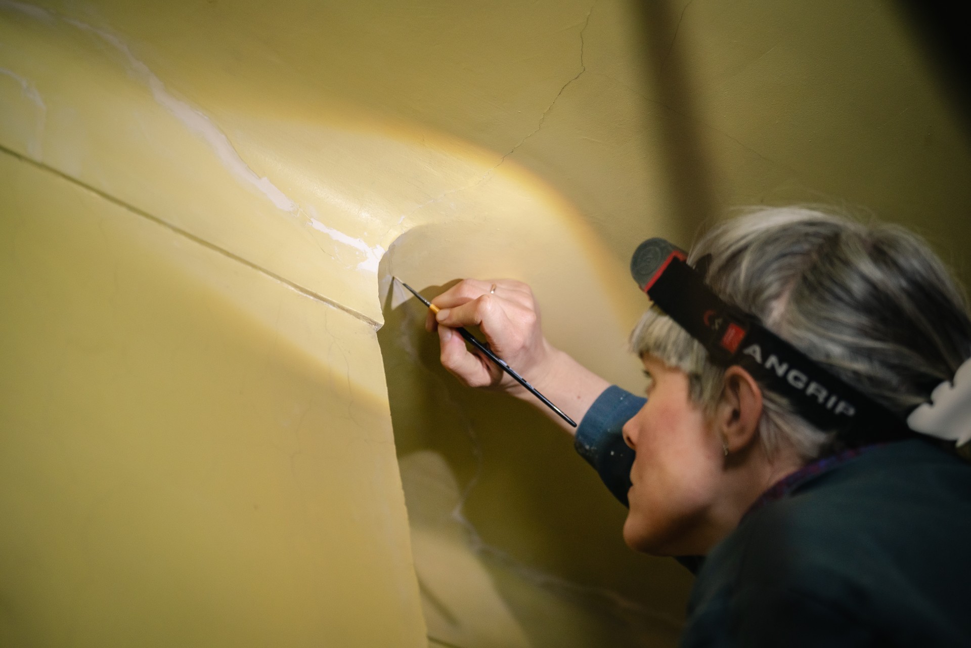 restauratrice werkt aan een scheur in de muur
