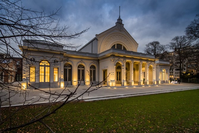 Een verlichte zaal Harmonie bij valavond in park Harmonie.