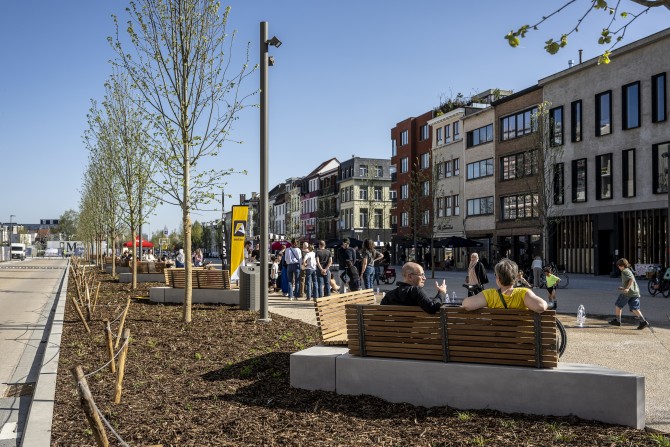Mensen op een plein omgeven door nieuw aangeplante bomen