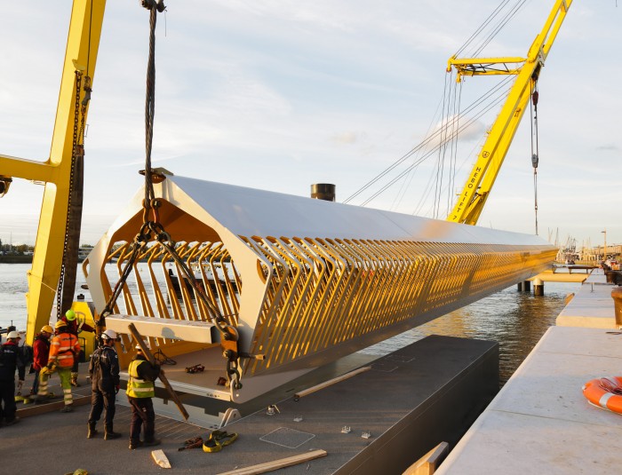 Een van de toegangsbruggen van het ponton van de nieuwe cruiseterminal wordt op haar plaats gelegd