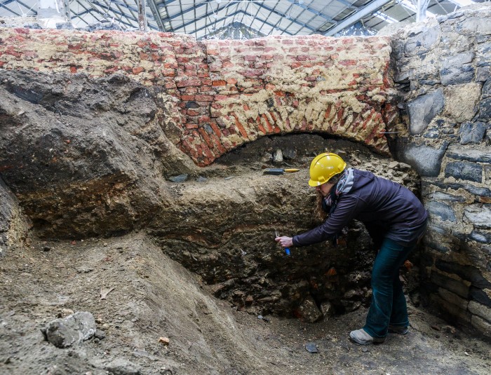 Archeologen onderzoeken de dempingslaag van de gracht in de historische burchtzone. Boven op de dempingslaag is een funderingsmuur (spaarboog) te zien van een later gebouw.