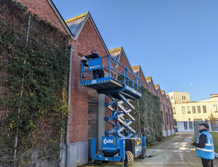 Arbeiders op een hoogtewerker installeren nestkasten aan de gevel van een voormalig spoorweggebouw in Park Spoor Noord.