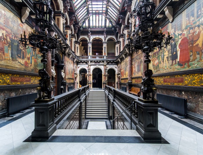 monumentale trap in het midden van het stadhuis met langs beide zijdes grote schilderingen op doek.