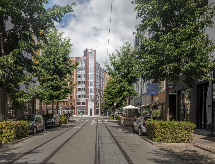 Zcht op een hoekpand vanuit een straat omgeven door bomen.